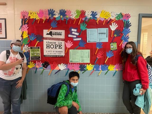 Photo of SADD Club members by a bulletin board with information for those addicted to heroin or facing other challenges.